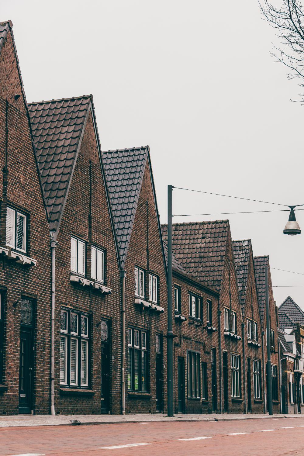 Rij bakstenen woningen met puntgevels aan een Nederlandse straat.