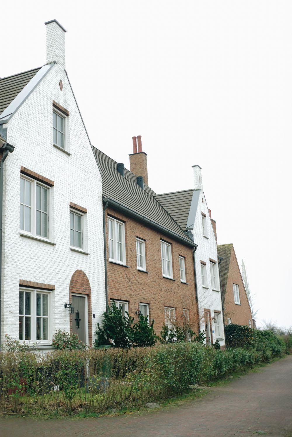 Twee-onder-een-kapwoning met witte en bakstenen gevel en een voortuin.